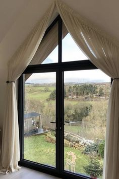 a large open window with curtains on the outside and an animal in the yard behind it