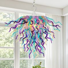 a colorful chandelier hanging from a ceiling in front of a window with white curtains