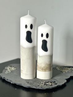 two white candles with faces painted on them