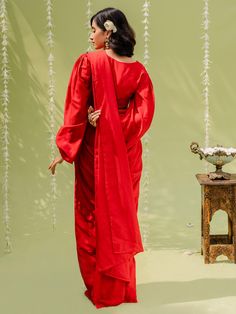 A two-piece hot red pre draped saree set from the Redpine Designs collection. This radiant red pre draped saree is paired with an embroidered blouse. The hot red color with salli, sequins work enhances the graceful crepe-georgette saree set. The hot red saree has beautiful pre draped pleats. The red crop top blouse has a V neckline with heavy embroidery at the front. The hot red blouse features pleated balloon sleeves with cuff style. This pre draped saree set is an ideal outfit for special even Bollywood Festive Sets With Draped Sleeves, Bollywood Style Festive Sets With Draped Sleeves, Festive Bollywood Sets With Draped Sleeves, Festive Diwali Sets With Draped Sleeves, Festive Sets With Draped Sleeves And Traditional Drape, Festive Dupatta With Draped Sleeves And Traditional Drape, Red Pre-draped Saree With Sheer Dupatta For Eid, Festive Dupatta With Draped Sleeves, Festive Choli With Draped Sleeves