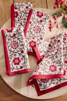 four red and white napkins on top of a wooden table next to a christmas tree