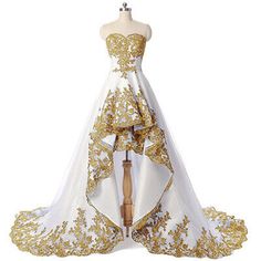 a white and gold wedding gown on a mannequin with an elaborate train,