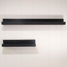 two black shelfs are hanging on the wall