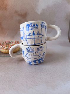 two blue and white cups sitting next to each other on top of a table covered in frosting