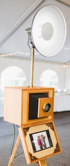 an old fashioned camera sitting on top of a wooden tripod with a speaker attached to it