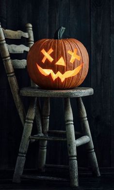 a carved pumpkin sitting on top of a wooden chair