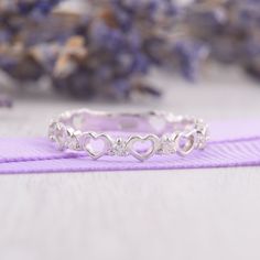 a heart shaped ring sitting on top of a purple ribbon next to some lavender flowers