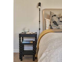 a bedroom with a bed, night stand and lamp on the nightstand next to it