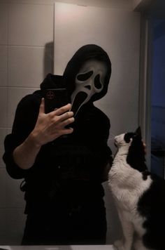 a person taking a selfie in front of a mirror with a cat looking at it