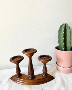 three wooden candlesticks and a cactus in a pot on a white tablecloth