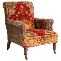 an ornately decorated chair with wooden legs and foot rest, in red velvet upholster