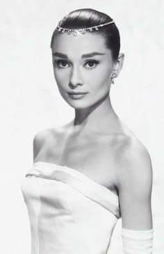 a black and white photo of a woman in a dress with gloves on her head