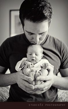 a man holding a baby in his arms and looking at the camera with an instagramr