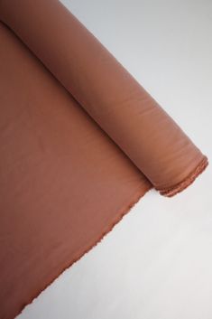 a roll of brown fabric sitting on top of a white table next to an orange object