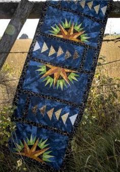 a quilt hanging on a fence in the grass