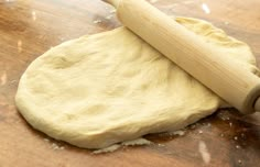 a rolling dough on a wooden table with a rolling pin