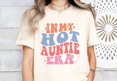 Step into the 'Aunti Era' with this retro-cool shirt, perfect for the hot auntie in your life. A fun pregnancy reveal or baby shower gift that's both trendy and nostalgic! * Q U I C K * F A C T S * ✺ 100% preshrunk cotton ✺ Wash and dry normally (on cool for best results) * S I Z I N G * ✺ Sizing is unisex so runs like men's, though not overly large ✺ Most women find their typical size works best, since they are meant to fit a touch loose* ✺ Size guide and fit: small - 2XL * S H I P P I N G * T Vintage Short Sleeve Tops For Gift, Retro Graphic Print Top For Gift, Retro Graphic Print Top As Gift, Retro Graphic Print Top, Vintage Screen Print Tops For Gift, Vintage Screen Print Tops As Gift, Retro Cotton Tops For Mother's Day, Retro Tops With Funny Print As Gift, Retro Funny Print T-shirt As Gift