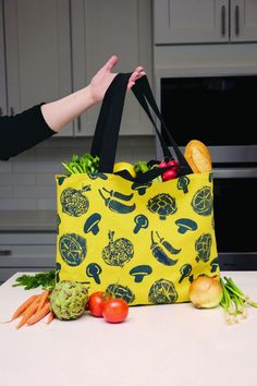 a person holding a bag full of vegetables on top of a kitchen counter next to an oven