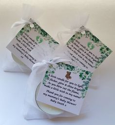 two white candles with green leaves and a poem on the top are wrapped in paper