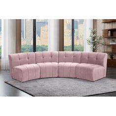 a pink curved couch in front of a window