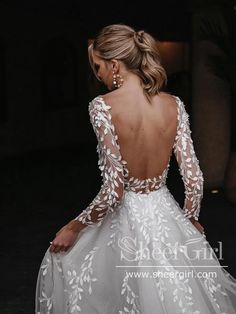 a woman in a white wedding dress with long sleeves and flowers on it's back