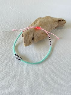 two bracelets on top of a piece of wood and some string with beads around them