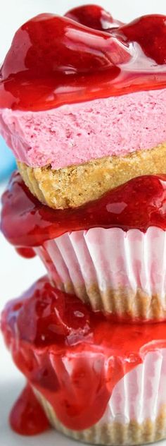 three cupcakes are stacked on top of each other covered in red and white icing