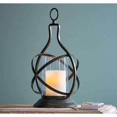 a candle is sitting in a glass container on a table next to some books and a book