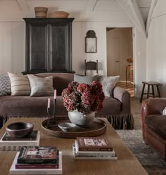 a living room filled with furniture and a wooden coffee table topped with flowers in a vase