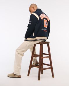 Classic bomber jacket in a soft faux wool fabric and relaxed-fit silhouette, featuring Denver Broncos varsity-inspired embroidered graphic patch details throughout, side pockets, snap-up front and tipping details at elastic cuffs and waistband. Retro Outerwear With Embroidered Graphics For Fall, Retro Fall Outerwear With Embroidered Graphics, Sporty Fall Outerwear With Embroidered Graphics, Varsity Outerwear With Embroidered Graphics And Baseball Collar, Fall Varsity Outerwear With Embroidered Graphics, Fall Varsity Outerwear With Letter Patch, Varsity Outerwear With Letter Patch For Fall, Collegiate Track Jacket With Letter Print For Fall, Collegiate Fall Track Jacket With Letter Print