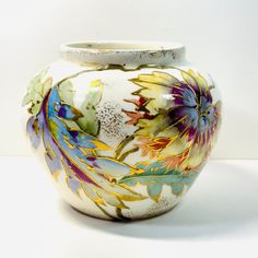 a white vase with flowers painted on it's sides and the bottom half is empty