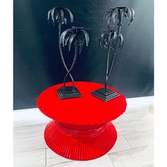 two metal sculptures sitting on top of a red table