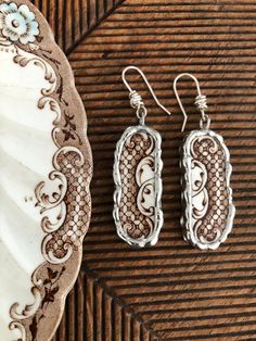 two pairs of earrings sitting on top of a plate next to a seashell shell