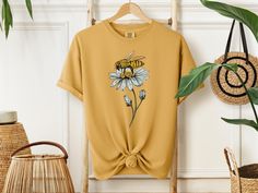 Bee Shirt Show your support for bee conservation with this beautifully designed bee shirt featuring a vibrant honey bee perched on a delicate flower. This nature-inspired graphic tee is perfect for those who love the outdoors, wildlife, and care about saving the bees.  Made with soft, breathable fabric, it's comfortable enough for everyday wear, whether you're gardening, enjoying nature, or simply showing your love for these essential pollinators. This bee shirt makes a thoughtful gift for natur Bee Conservation, Women Nature, Bee Shirt, Enjoying Nature, Save The Bees, Comfort Color, Gifts For Nature Lovers, Shirt For Women, Delicate Flower