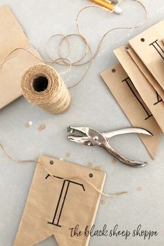 scissors, twine and tape are on the table next to some brown paper tags