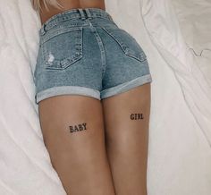 a woman laying on top of a bed with her back turned to the camera and tattoos on her legs