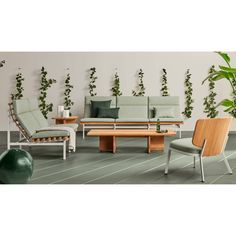 a living room filled with lots of furniture next to a wall covered in green plants