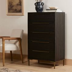 a black dresser sitting next to a white chair