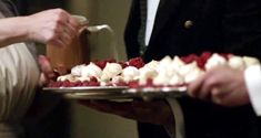 two people are serving themselves food on a platter with red and white toppings