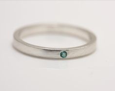 One petite 1.75 mm emerald is flush set in sterling silver in this striking minimalist ring. It can be worn by itself or as an accompaniment to another ring, as in the third photo, where it is paired with a white sapphire ring (see listing on my Etsy page).  This ring would make a beautiful engagement or wedding ring. This ring also works well as a stack ring.Please allow up to 3 weeks processing time for filling your order.Please contact me for information if you are not clear on how to measure Modern Sterling Silver Stackable Rings Round Cut, Modern Round White Gold Emerald Ring, Modern Sterling Silver Stackable Rings With Tension Setting, Sterling Silver Stackable Rings With Single Diamond, Minimalist Sterling Silver Stackable Rings With Round Cut, Emerald Ring With Single Diamond Gift, Minimalist Round Sterling Silver Stackable Rings, Modern White Gold Emerald Rings, Classic Sterling Silver Emerald Ring With Round Band