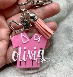 a person holding a keychain with a pink house on it and the words b is giving