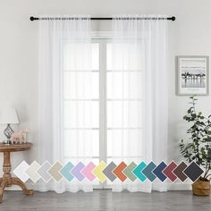 a living room filled with furniture and windows covered in white sheer curtain panels next to a wooden table