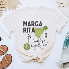 Step into the vibrant spirit of Mexico with our Margarita Shirt! This sophisticated tee celebrates the iconic cocktail's origins with a stylish design featuring the recipe, birthplace, and the sun-kissed year of its inception in the 1938. Emblazoned with the Spanish phrase "la bebida que hace brillar el sol" (the drink that makes the sun shine), this shirt exudes the essence of a sunlit fiesta. Whether you're enjoying happy hour, exploring Mexico's rich culture, or commemorating Cinco de Mayo, t Cinco De Mayo Screen Print Crew Neck T-shirt, Cinco De Mayo Graphic Tee With Short Sleeves, Cinco De Mayo Graphic T-shirt, Cinco De Mayo Graphic Cotton T-shirt, Cotton Graphic Tee For Cinco De Mayo, Cinco De Mayo Graphic Print T-shirt, Cinco De Mayo Funny Print Crew Neck T-shirt, Cinco De Mayo Funny Print Crew Neck Top, Cinco De Mayo Graphic Tee With Crew Neck