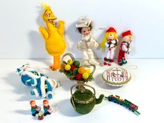 several toy figurines and toys are arranged on a white surface, including an old fashioned teapot