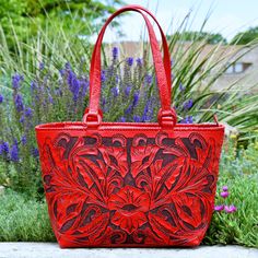 A timeless piece to add to your collection! This gorgeous and unique statement bag is all tooled leather and all yours! Red floral tooled front and basket weave tooled back are accentuated with a black patina. Embossed handles attached with leather covered D-rings for durability, and lacing along the seams. Top zipper closure. Suede lined inside, with two open pouch pockets and a zipper pocket. Red Hand Tooled Rectangular Bag, Hand Tooled Red Rectangular Bag, Red Hand-tooled Rectangular Bag, Red Hand Tooled Bag For Daily Use, Radiant Red, Statement Bag, Western Look, D Rings, Tooled Leather