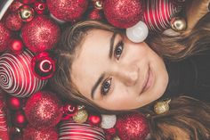 a woman laying in a tub filled with red and gold christmas ornaments on top of her head