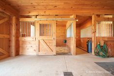 the inside of a horse barn with wood paneling and stalls on either side of the door