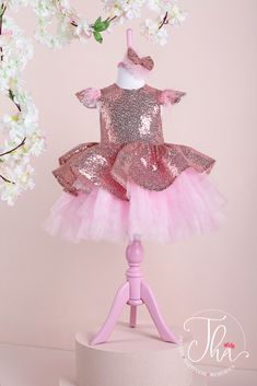 A rose gold tutu princess dress which has cap sleeve, feathers on arms, sequin fabric top, and pink layered skirt. Elegant Pink Glitter Sequin Dress, Princess Embellished Tutu Dress For Party, Princess Style Embellished Tutu Dress For Party, Pink Glitter Dresses For Wedding, Pink Glitter Dress For Wedding, Party Pageant Dress With Sequins And Glitter Tulle, Party Pageant Dress With Sequins On Glitter Tulle, Pageant Dress With Sequins In Glitter Tulle For Party, Pink Princess Sequin Dress For Weddings