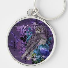 an owl sitting on top of a purple flower covered keychain with flowers around it