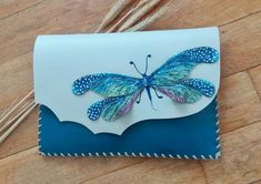 a blue and white card with a dragonfly on it's back, sitting on a wooden floor